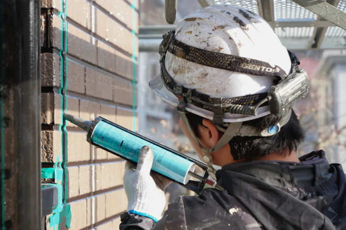 丁寧に塗装業務を行うスタッフの後ろ姿
